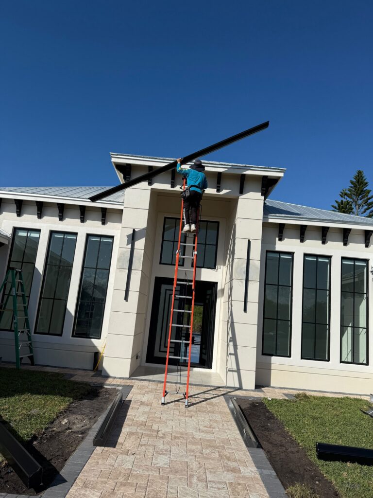 Crew lifting a new seamless gutter section into place on a replacement job